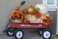 a wagon filled with pumpkins and gourds sitting on the side of a house