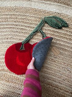 a person is holding an apple shaped object on the floor next to another piece of cloth