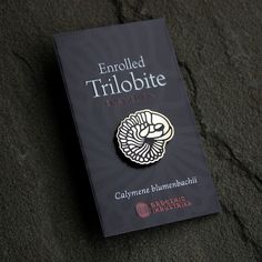 a brooch sitting on top of a book with the title enrolled trilobite