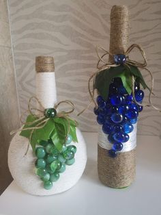 two wine bottles decorated with blue and green grapes