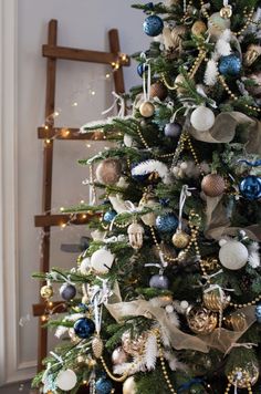 a decorated christmas tree with blue, gold and white ornaments on it's branches