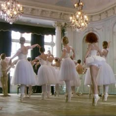 a group of ballerinas are dancing in a ballroom