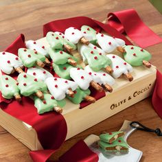 a wooden box filled with green and white cookies on top of a red table cloth