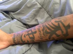 a man with tattoos on his arm laying in bed