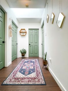 a hallway with green doors and rug on the floor