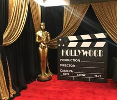 an oscar statue next to a movie clapper on a red carpet with gold drapes