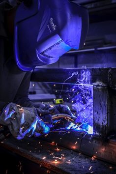 welder working on an industrial piece of metal with blue light coming from the machine