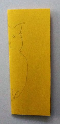 a yellow piece of paper with a drawing of a cat on it's side