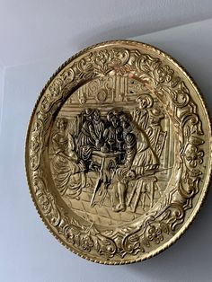 a gold plate with an ornate design on the front and sides, hanging on a wall