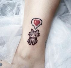 a small pixel heart tattoo on the ankle with an image of a cat holding a balloon