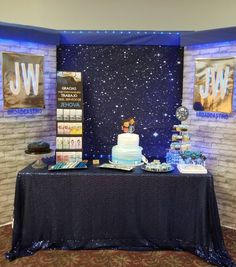 a table topped with a cake covered in blue frosting and surrounded by other desserts