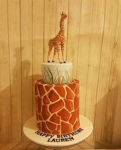 a giraffe birthday cake is on display in front of a wooden wall with wood planks