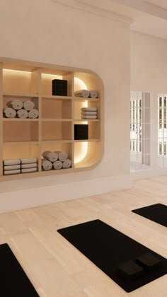 there is a yoga room with black mats on the floor and white towels on shelves