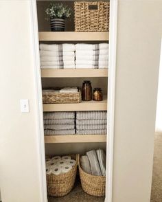 an open closet with towels and baskets on the shelves