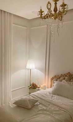 a bedroom with a chandelier hanging from the ceiling next to a white bed