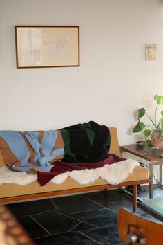 a living room with a couch, table and potted plant on the floor in front of it