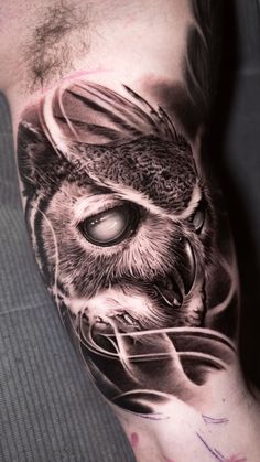 an owl tattoo on the left arm and leg, with a glass in it's beak