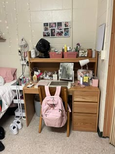 a pink backpack sitting on top of a wooden desk next to a chair and dresser