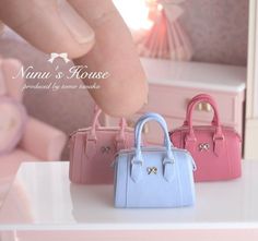 three small purses sitting on top of a white table next to pink and blue boxes