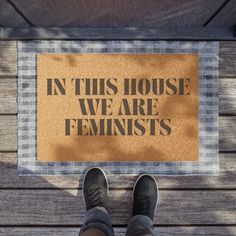 someone standing in front of a door mat that says in this house we are feminists