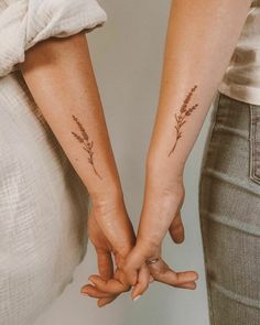 two people holding hands with small tattoos on their arms and the other hand behind them