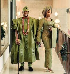 a man and woman dressed in traditional african clothing walking down a hallway with canes