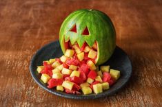 a carved pumpkin is sitting on a plate with chopped fruit in it's mouth