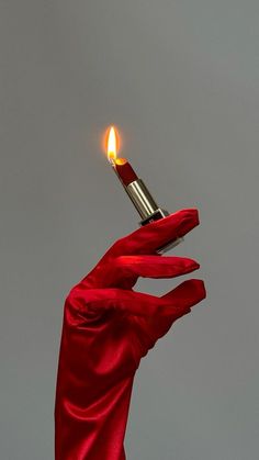 a person in red gloves holding a lighter up to the sky with their hand on it