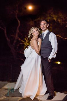 a bride and groom posing for a photo at night