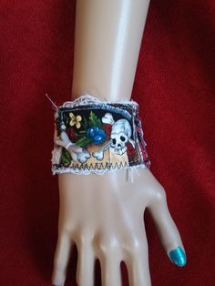 a hand with a bracelet on it that has a skull and flowers on the wrist