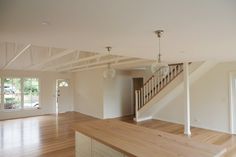 an empty living room with hard wood flooring and white railings on the second story