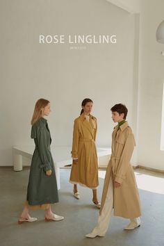 three women in trench coats are standing near each other and looking at the same person