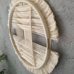 a round wall hanging made out of woven material with fringes on the bottom and sides