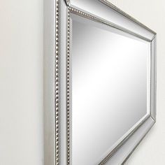 a mirror mounted to the side of a wall with beaded trimmings on it