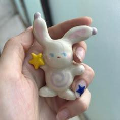 a hand holding a small white rabbit figurine with stars on it's nose