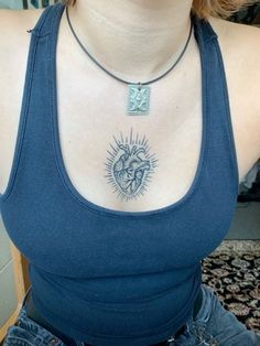 a woman wearing a blue tank top with a heart tattoo on her chest