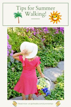 a woman in a red dress and white hat walking down a path with flowers on it