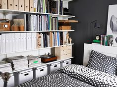 a black and white bedroom with polka dot bedding, bookshelves and drawers