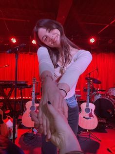 two people are shaking hands in front of microphones and guitar stands at a concert