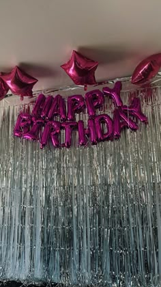 purple balloons and streamers are hanging from the ceiling in front of a happy birthday sign