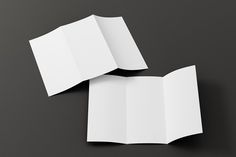 two folded white paper on a black surface with one open and the other half closed