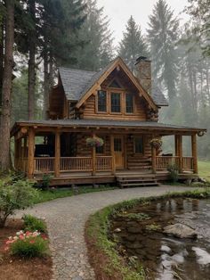 a log cabin sits in the middle of a forest next to a small pond and stream