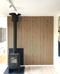 a room with a wood stove next to a wall covered in vertical striped walls and wooden flooring