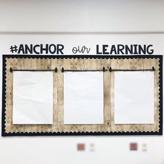 an anchor our learning sign hanging on the wall with three white paper squares attached to it