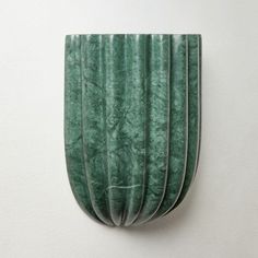 a green sculpture is hanging on the wall