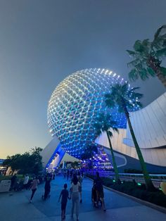 people are walking around in front of spaceship shaped building