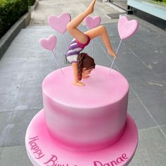 a pink cake with a figure on top and hearts in the shape of a woman