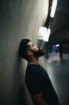 a man leaning against a wall with his eyes closed