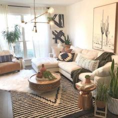 a living room filled with lots of white furniture and plants on top of rugs