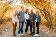 a group of people standing next to each other in front of trees with yellow leaves